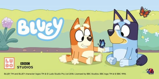 Two cartoon dogs, Bluey and Bingo sit on grass. Bingo, holds a butterfly. The'Bluey' logo is written above them. Another butterfly flies next to Bluey and a ladybug crawls next to Bluey.