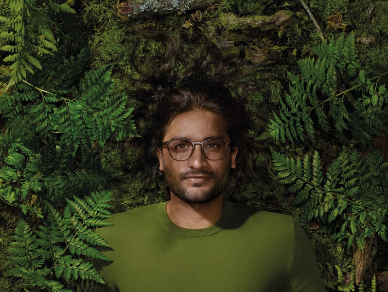 Man wearing Reframe glasses and lying in green leaves